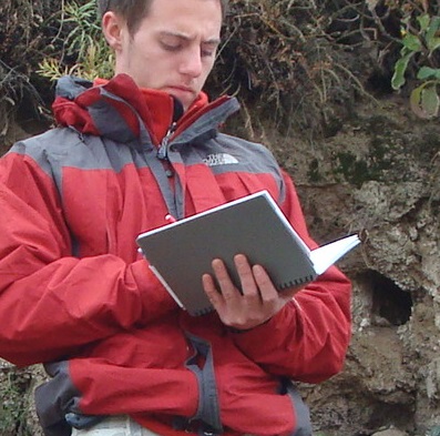 Mineral exploration geologist on site taking details down in his geological field notebook.