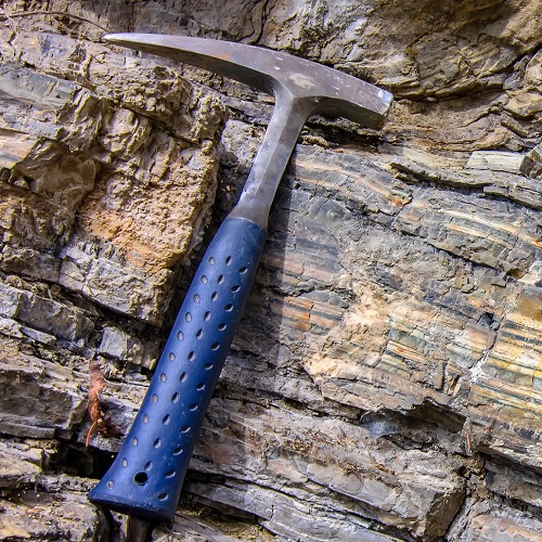 Geologica hammer in use as a scale against folds in a gneiss rock outcrop.
