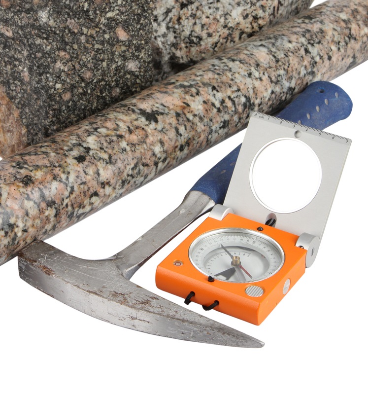 Essential geology field equipment including a rock pick and compass clinometer.